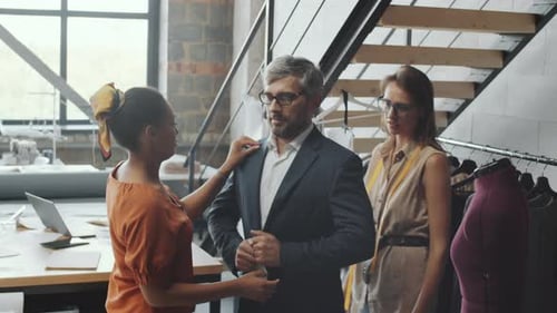 Des tailleurs aident un client masculin à essayer un nouveau costume