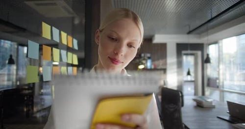 Cute Girl Manager in the Office Writes Down Ideas of Her Colleagues on a Sticker