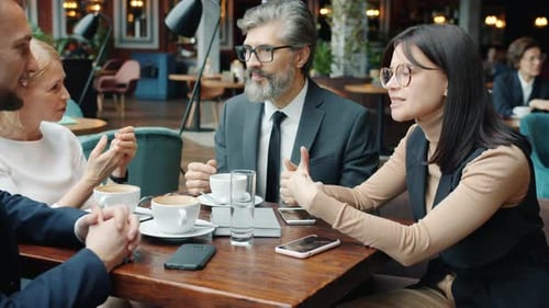 Men and Women Colleagues Talking in Restaurant at Table Enjoying Conversation