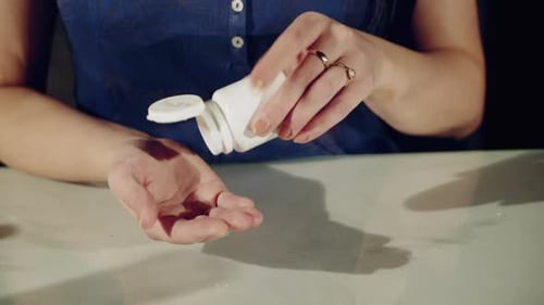 One step from death. Close up of pills in hands of young depressed girl holding them
