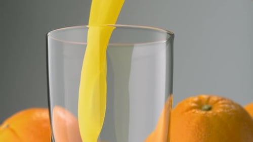 Orange Juice Pouring Into a Clear Glass