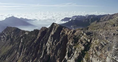 Aerial View of Rocky Mountain Cliff. Beautiful Landscape in Background, Clouds Cover Lower Mountain