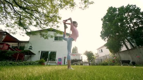 The Child Is Engaged in Acrobatics at Sunset in Back Yard. Slow Motion