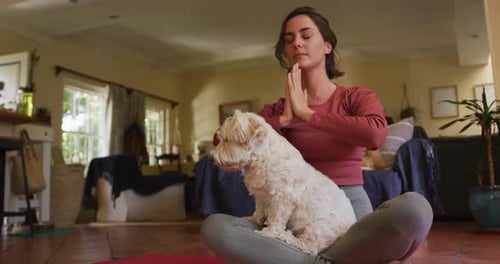 Woman Meditating with Dog on her Lap Indoors