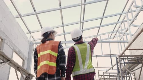 Asian engineer worker in protective helmet walking to checking at house building construction site