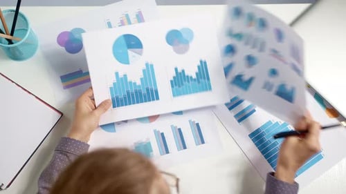 Eine Geschäftsfrau hält statistische Daten und Diagramme von Finanzberichten in ihren Händen.