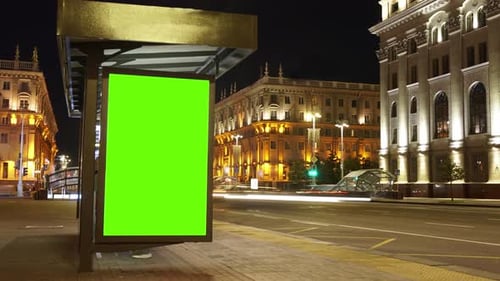 Billboard with a chroma key green screen on n bus stop at night.