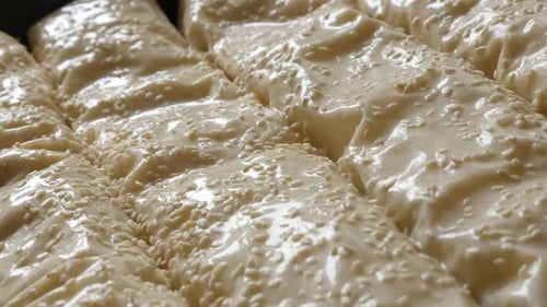 Sesame sprinkling over oiled homemade filo pie with cheese and spinach close-up 4K 2160p 30fps UHD