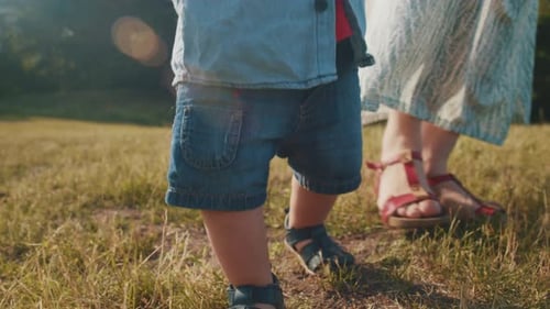 Child Takes the First Steps Walking in the Park with Mom