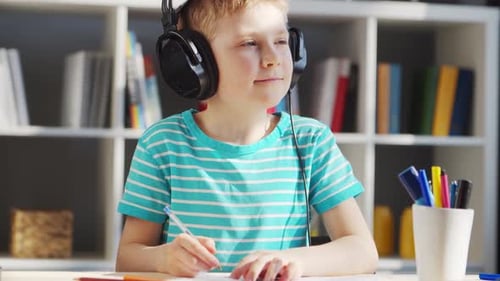 Boy Writing with Headphones On