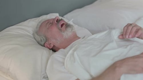 Senior Man Resting Comfortably in Bed at Home