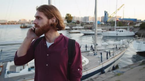 Homem sorridente falando no telefone perto do rio