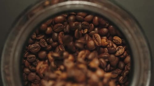 Brown Coffee Beans Filling Glass Jar Close Up