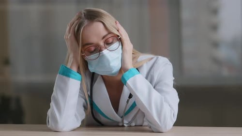 Tired Woman Doctor in Mask With Hands on Head