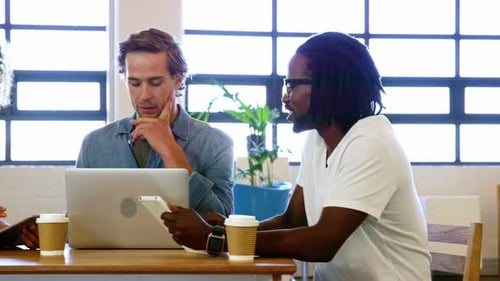 Colleagues discussing with each other over laptop