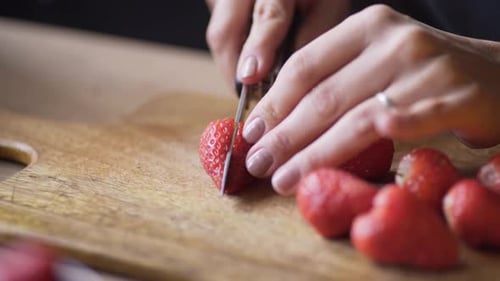 Woman cutting fresh strawberries on cutting board