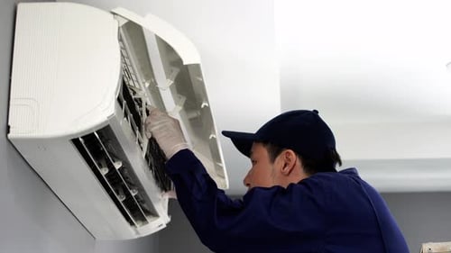 technician service placing back clean filter into air conditioner