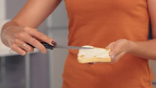 Woman Spreads Cream Cheese on Toast in Kitchen