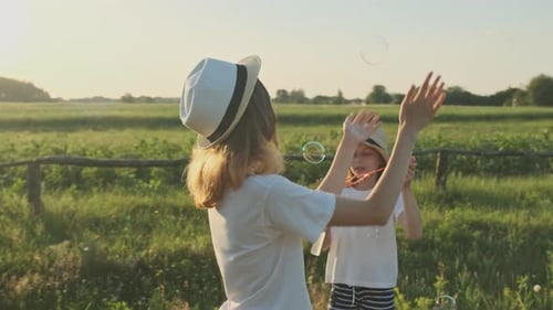 Children Blowing Soap Bubbles, Two Girls Playing in Nature