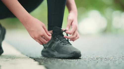 Running shoes runner woman tying laces for summer run in forest park.