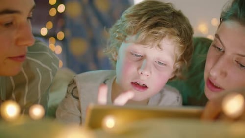 Boy Reading Bedtime Story on Tablet with Lesbian Parents