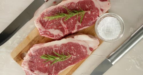 Two Cuts of Raw Steak with Rosemary and Salt
