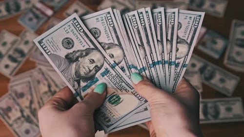 Woman's Hands Fanning Pile of $100 Bills