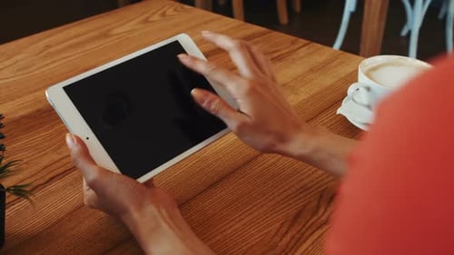 Woman using digital tablet while having coffee