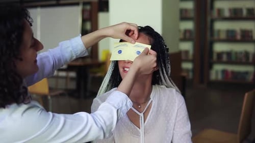 Playful Women with Paper Eyes in Bright Room