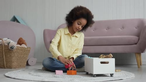Niña afroamericana construye una torre con un kit de construcción de madera de colores