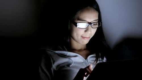 Woman Using Tablet Device at Night Indoors