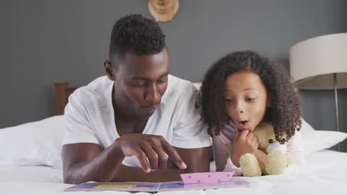 Affectionate Father Reading Story to Child on Bed