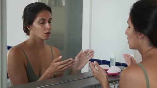 Woman Applying Moisturizer to Face in Bathroom
