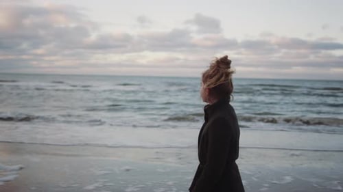 Girl In Black Walking Along Beach
