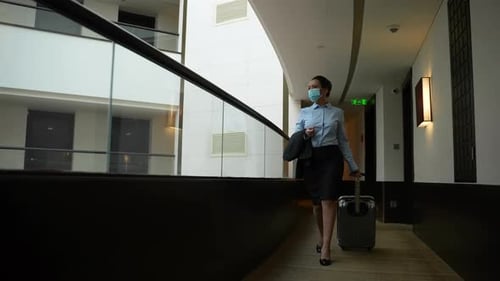 Masked Businesswoman Walking Along Hotel Corridor