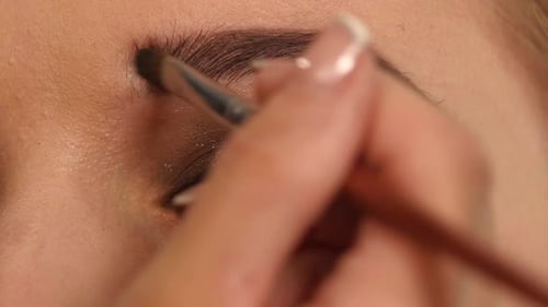 Make-up für das junge Mädchen: Schöne Form der Augenbrauen mit einem Kosmetikpinsel, Nahaufnahme. Zeitlupe