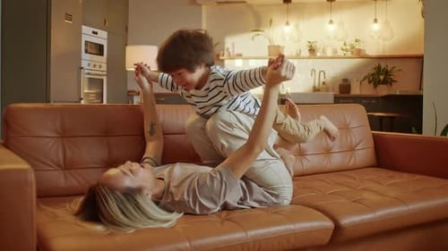 Loving Mother Playing with Child on Couch at Home