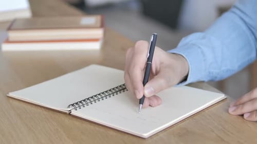 Hand Writing in Notebook at Desk