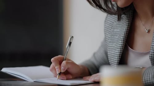 Woman Writes in Notebook at Desk Close Up