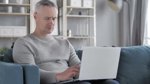 Man Working on Laptop at Home on Couch