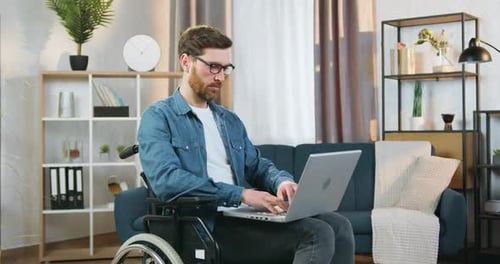 Man in Wheelchair Working on Laptop at Home