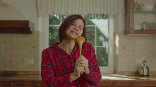 Woman Singing with Spoon in Kitchen