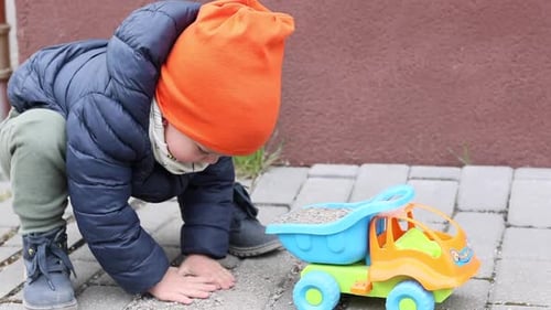 Child Plays with Toy Truck on Paved Surface