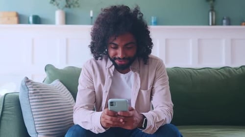 Young Adult Using Smartphone While Sitting on Couch