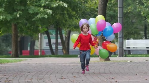 Happy Child Runs with Balloons in Park