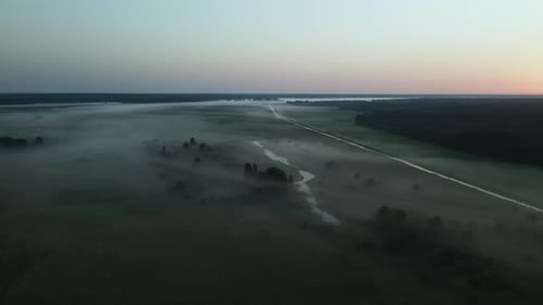 Foggy dawn in the countryside. Foggy river valley and rising sun. Aerial photography.
