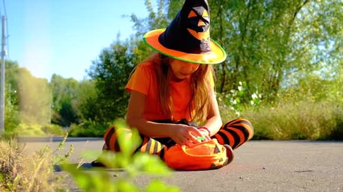 Girl in Halloween Costume Looking at Candy Outdoors