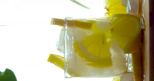 Pouring Water into Glass of Lemonade with Ice