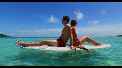Two people happy together on marine lagoon beach voyage by shallow sea with white sandy background o