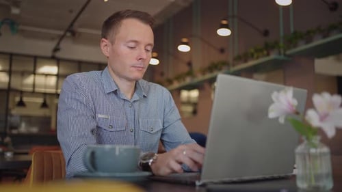 Man Working on Laptop in Coffee Shop